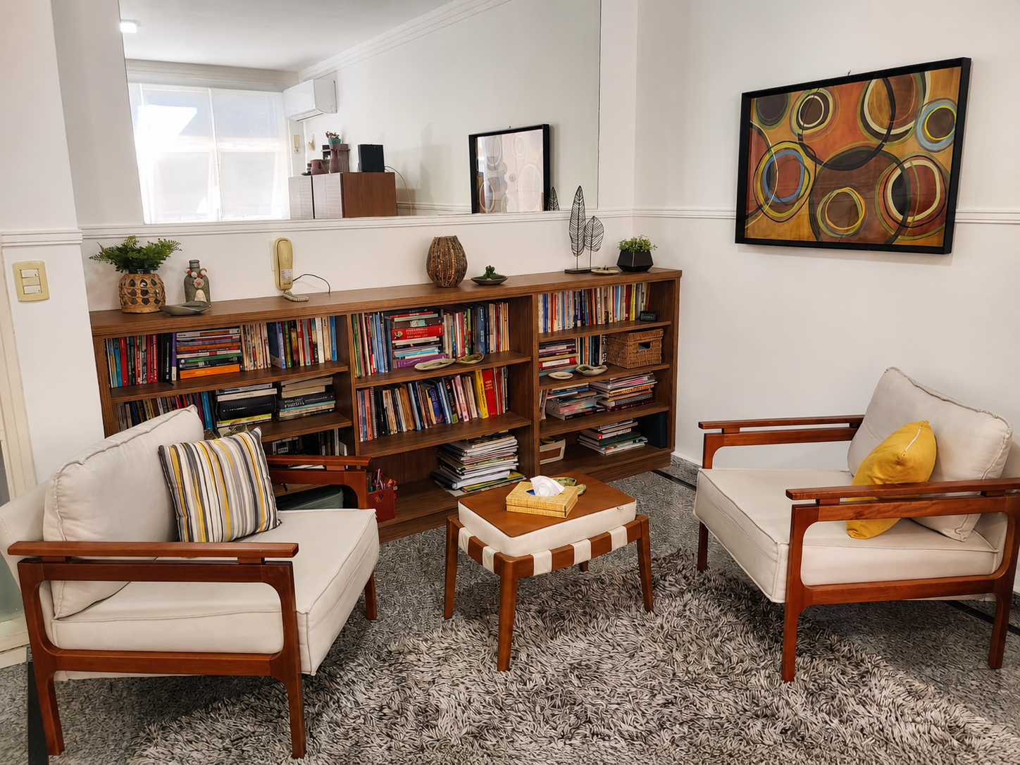 Sala de atendimento com poltronas e estante de livros